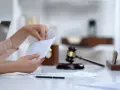 Dłoń otwiera kopertę na biurku z młotkiem sędziowskim i dokumentem "contract". Czy alimenty się przedawniają?