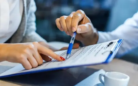 Dwie osoby analizują dokumenty, być może związane z **bnp paribas zajęcie komornicze**. Jedna wskazuje palcem, druga trzyma długopis.