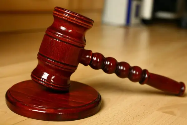 Młotek sędziowski na drewnianym stole. Symbolizuje sprzedaż mieszkania z wpisem komorniczym i decyzje prawne.
